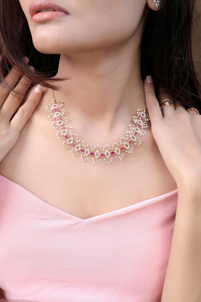 Close-up of a woman wearing a luxurious pearl and ruby necklace, showcasing elegance and style.
