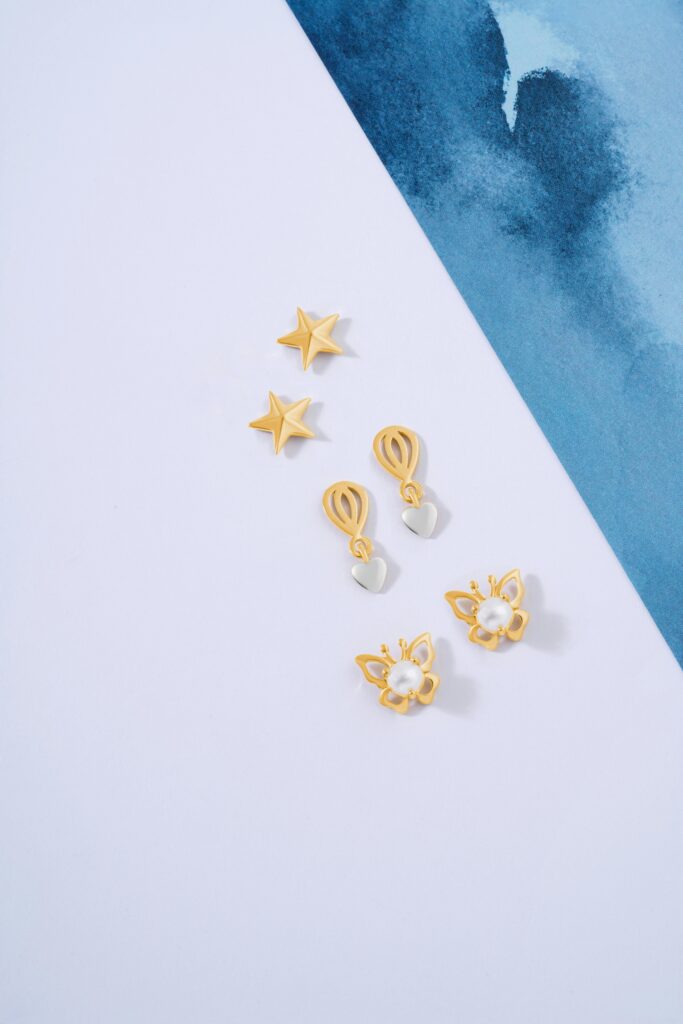 A creative display of gold and silver earrings on a minimalist blue and white background.