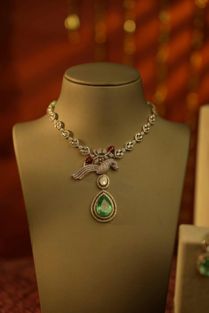 Luxurious diamond necklace featuring an emerald teardrop pendant on a display stand, perfect for jewelry enthusiasts.