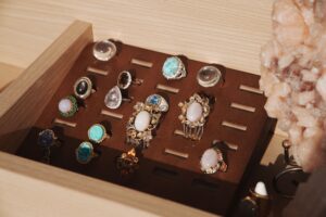 A neatly organized jewelry box showcasing various gemstone rings with a natural crystal accent.